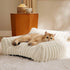 Golden cat lounging on a plush, cozy white textured pet sofa in a modern indoor setting