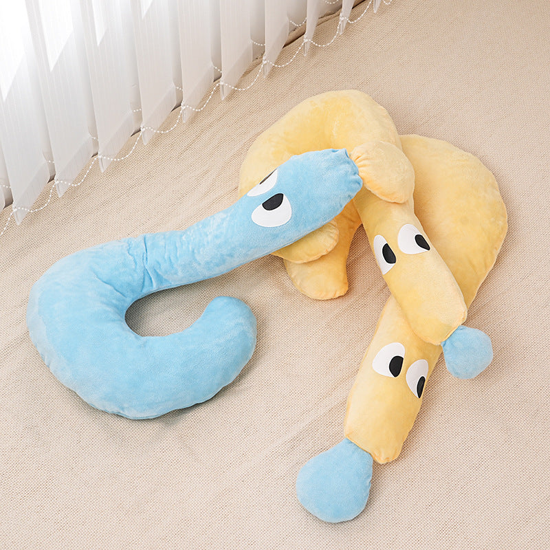 Two plush pet pillows shaped like playful animals in soft blue and yellow tones on a neutral floor